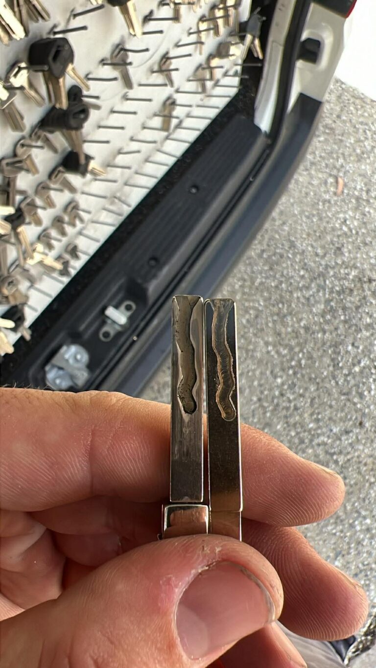 Two freshly cut key blades compared against a board of key blanks in the mobile workshop